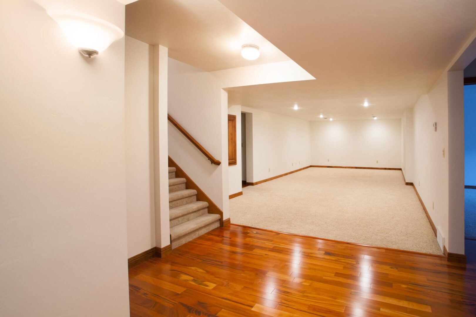 Spacious room with wooden floor and stairs.