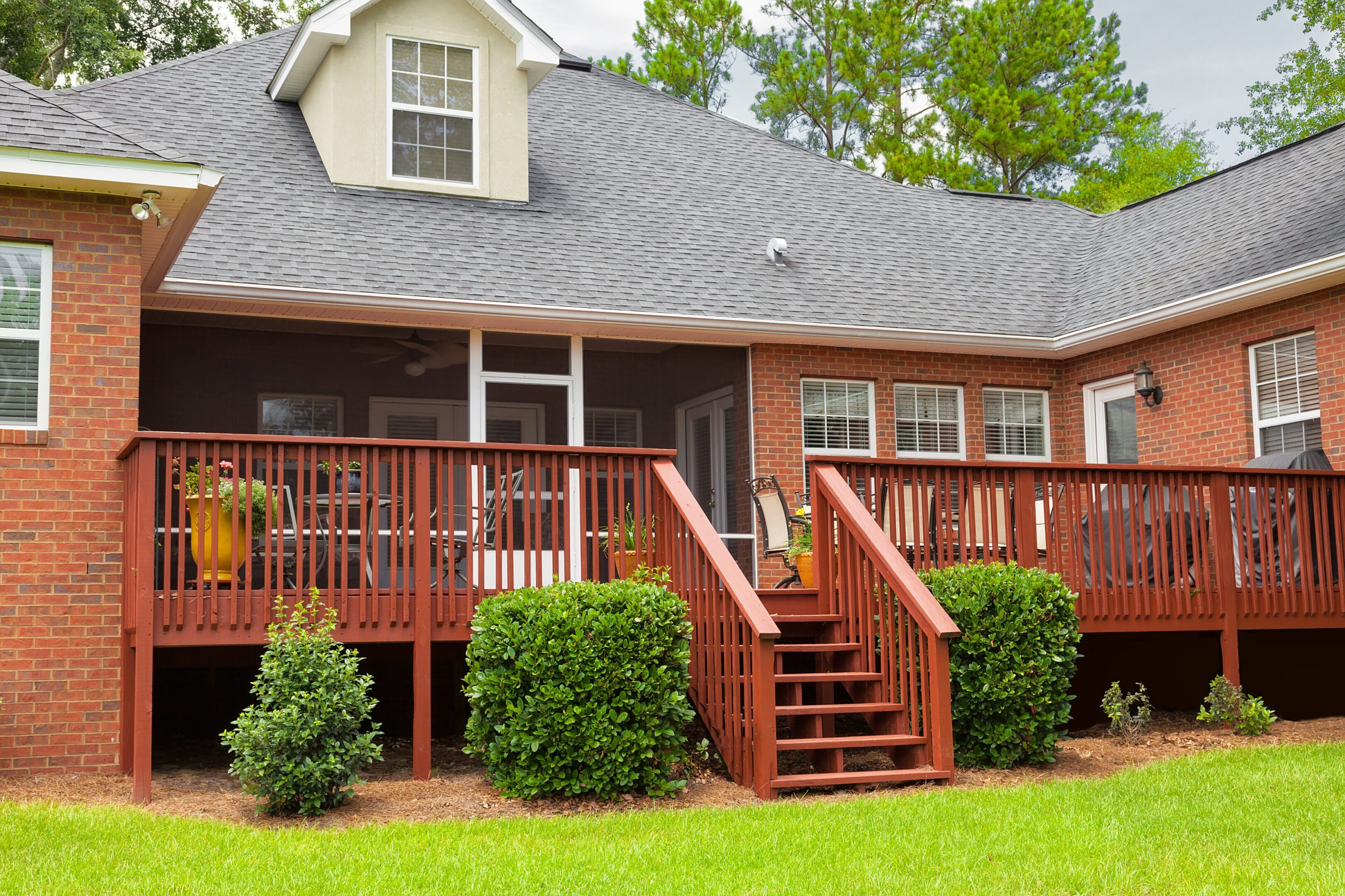 A house with a deck and steps leading to the front door.