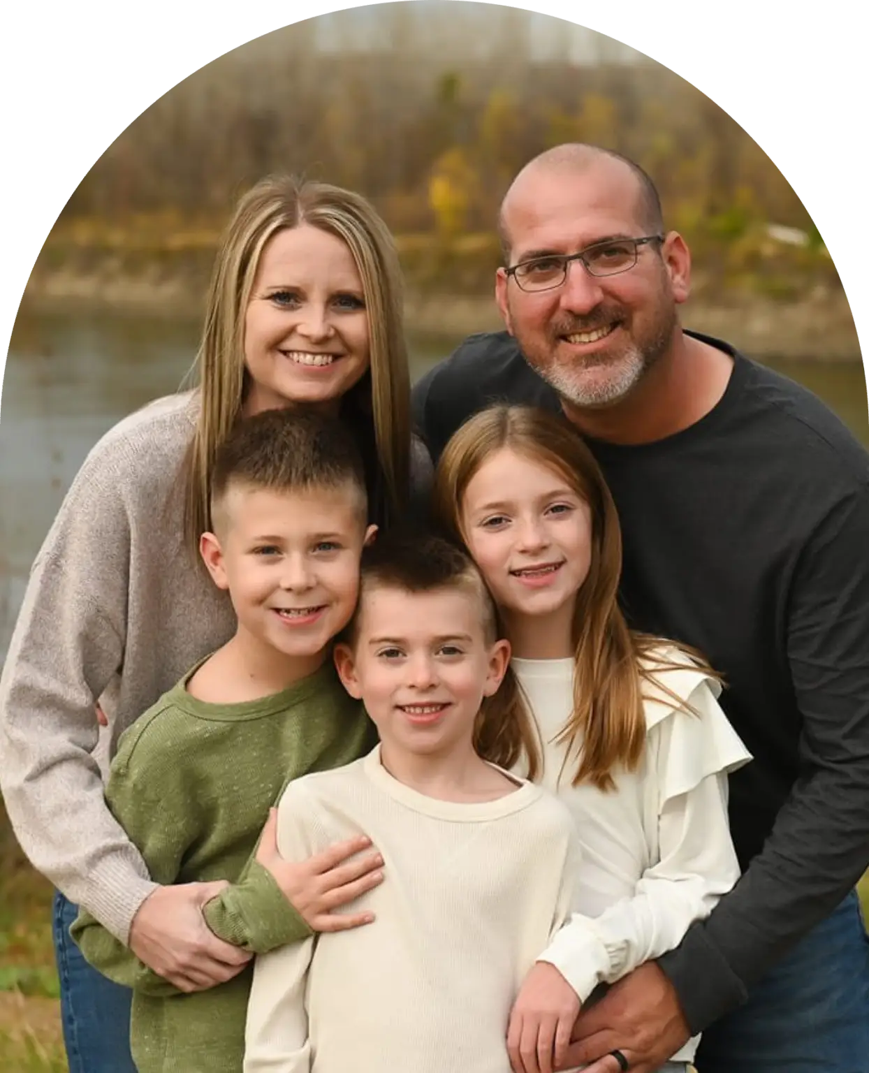 A family posing for a picture in front of the water.